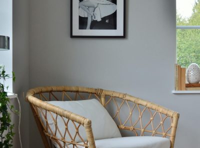A stylish wicker chair in a Scandinavian-designed room with a framed photo on the wall.
