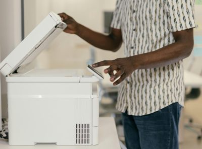Person operating photocopier in modern office setting, engaging with technology.